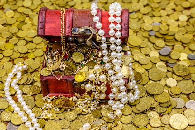 Vintage Schatzkiste voller Goldmünzen und Schmuck auf einem Hintergrund von Goldmünzen