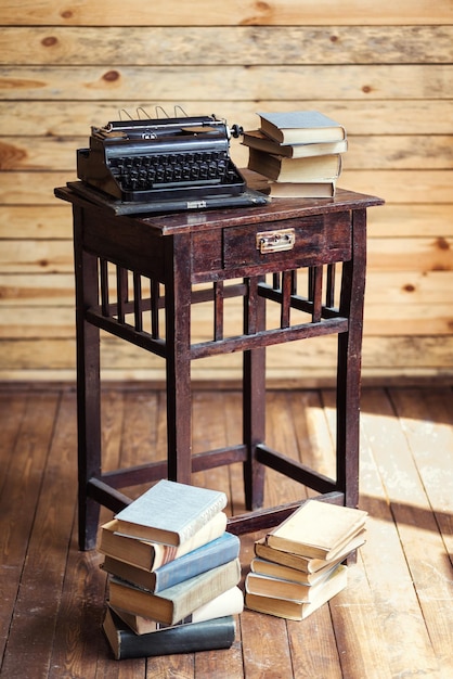 Vintage-Schreibmaschine und Bücher auf dem Tisch mit leerem Papier auf Holzschreibtisch