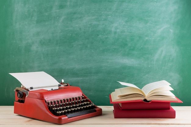 Vintage-Schreibmaschine und Bücher auf dem Tisch mit leerem Papier auf Holzschreibtisch