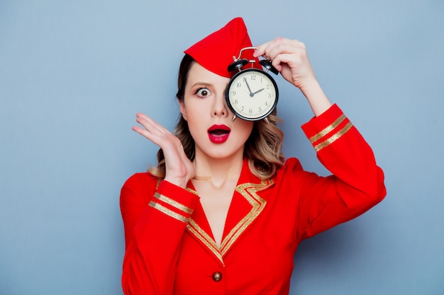 Vintage stewardess in roter uniform mit wecker