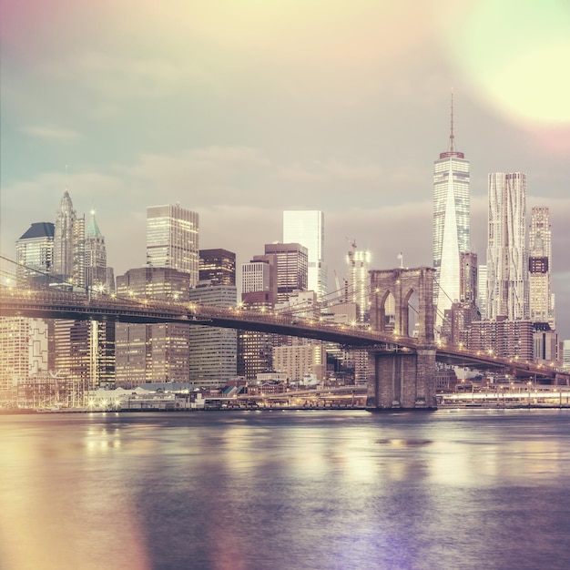 Vintage-Stil Blick auf die Brooklyn Bridge und die Skyline von Lower Manhattan in New York City mit Stadtbeleuchtung USA