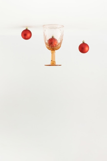 Vintage Trinkglas und rote Christbaumkugeln Dekor auf den Kopf gestellt auf weißem Hintergrund