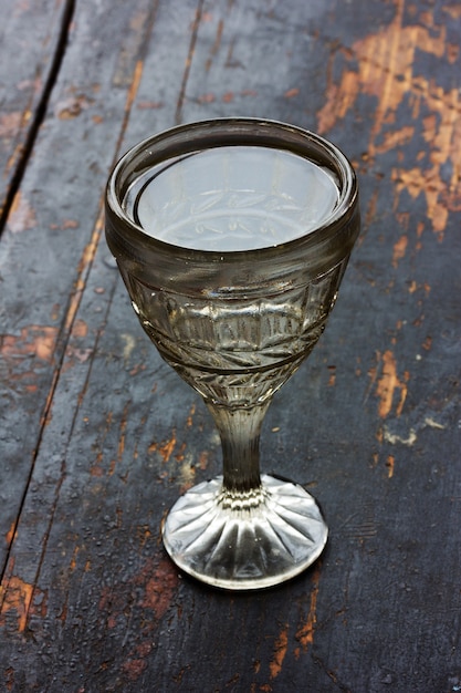 Vintage vaso con vodka en una vieja mesa de madera negra