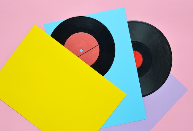 Vinylplatten auf einer farbigen Pastelloberfläche. Retro musikalische Attribute aus den 80ern. Draufsicht, Minimalismus. Speicherplatz kopieren