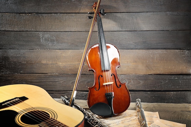 Violão acústico saxofone soprano violino flauta e folhas de notas em fundo de madeira