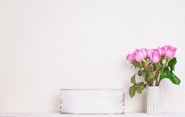 Violette Rosenblüten in Vase auf Holztisch mit Platz für Kopierraum