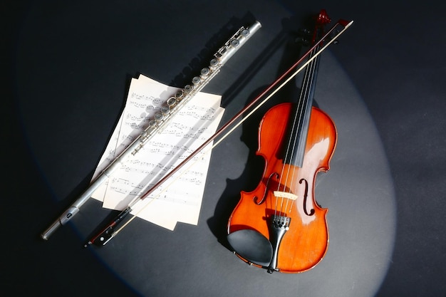 Violín y flauta con notas musicales sobre fondo oscuro