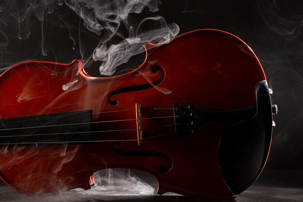 Violín y humo maravillosos detalles de un hermoso violín con humo en el entorno fondo oscuro enfoque selectivo