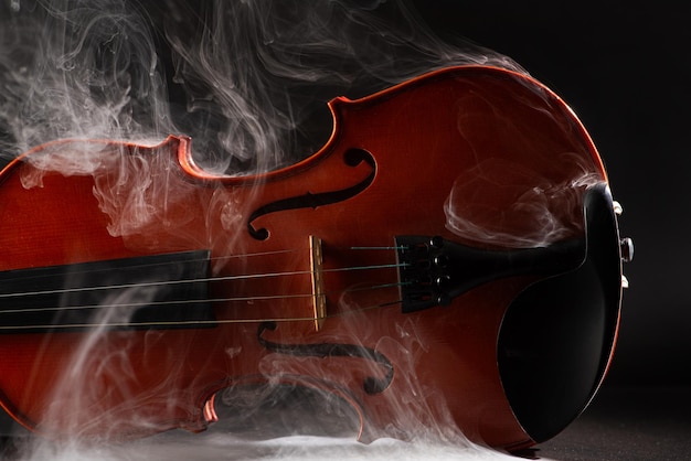 Violín y humo maravillosos detalles de un hermoso violín con humo en el entorno fondo oscuro enfoque selectivo