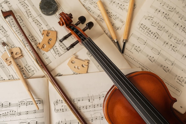 Foto violine und bogen auf noten in einer reparaturwerkstatt für musikinstrumente