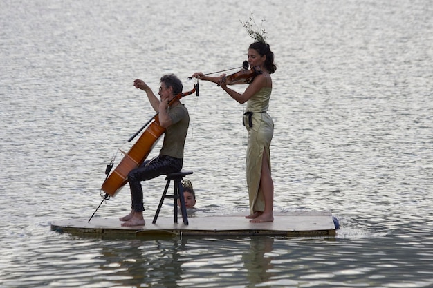 Foto violinistas jugando en el lago