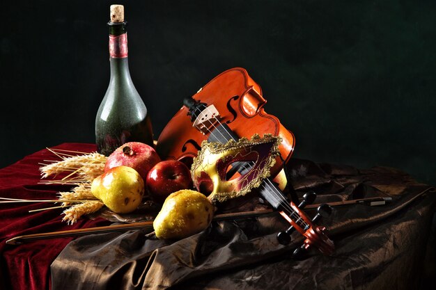 Violino e máscara teatral no tecido ao lado de frutas suculentas