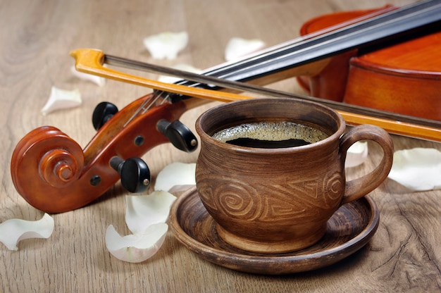 Violino e uma xícara de café. café e pétalas de rosa