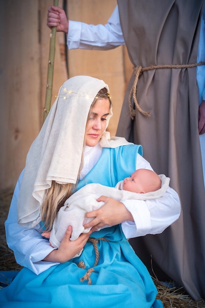 Virgen María sosteniendo al bebé Jesús en un belén tradicional