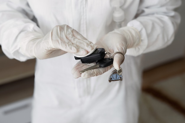 Foto virólogos, personas con trajes protectores realizan la desinfección en el departamento. limpie las llaves del automóvil durante un brote del coronavirus. covid-19