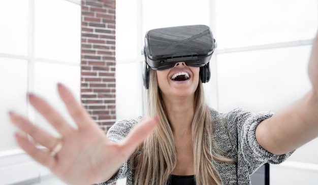 Virtual-Reality-Brille Selbstbewusstes lächelndes Mädchen, das sich glücklich fühlt, während es ein Virtual-Reality-Gerät trägt und auf die Symbole auf dem transparenten Bildschirm zeigt