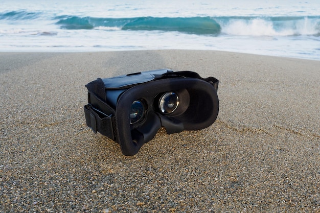 Virtual-Reality-Headset auf Sand des tropischen Strandes über Meer und Himmelshintergrund