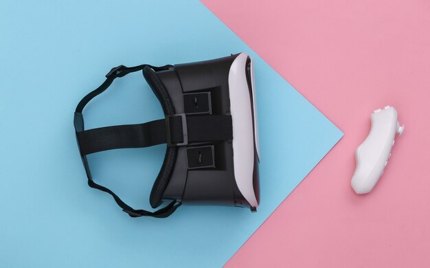 Foto virtual-reality-headset mit joystick auf rosa blauem pastellhintergrund. ansicht von oben. fliege lag. minimalismus