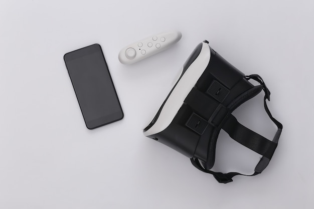 Virtual-Reality-Headset mit Joystick und Smartphone auf weißem Hintergrund. Ansicht von oben. Flay legen