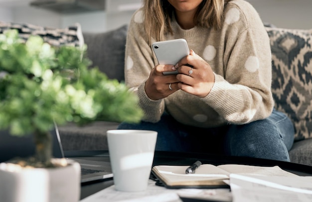 Virtuell mit Kollegen auf dem Laufenden bleiben Schnappschuss einer jungen Frau, die ihr Handy benutzt, während sie von zu Hause aus arbeitet