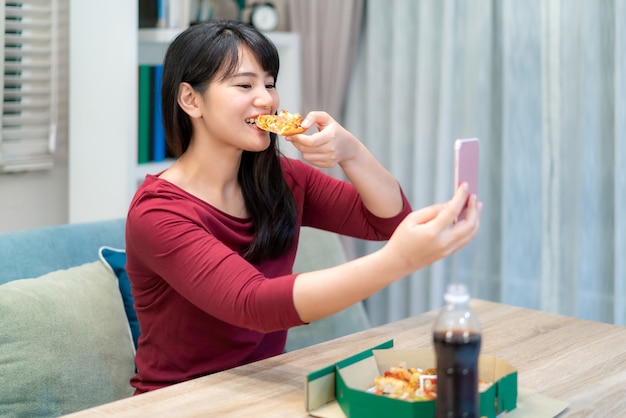 Virtuelle Happy Hour der asiatischen Frau, die Abendessen trifft und Pizza zusammen online isst