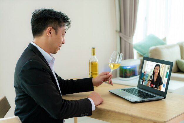 Virtuelle Happy Hour Meeting-Party des asiatischen Mannes und das Trinken des weißen Traubenweins online zusammen