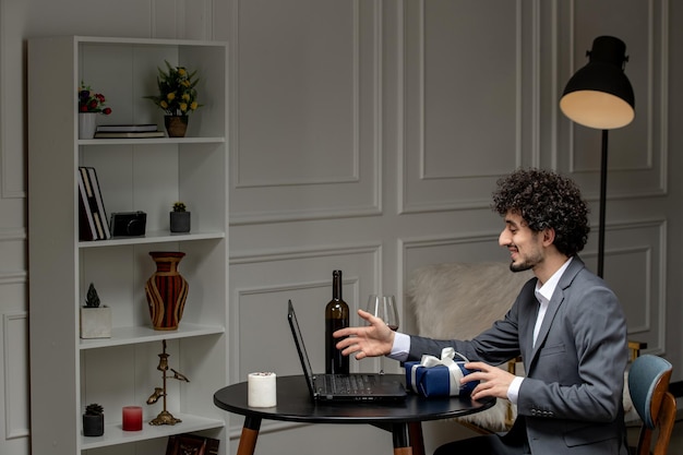 Virtuelle Liebe, gutaussehender, süßer Kerl im Anzug mit Wein bei einem Ferncomputer-Date, der über Videoanruf spricht