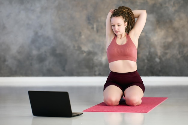 Virtuelle Live-Streaming-Klassen mit Laptop von einer Frau mit Dreadlocks während des Trainings.