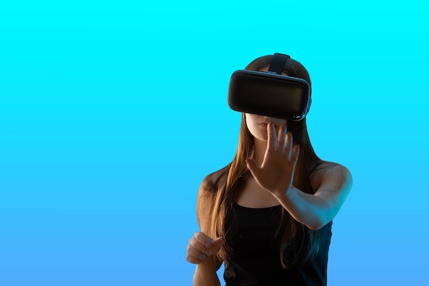 Virtuelle Realität und die digitale Welt. Mädchen-Gamer im VR-Helm auf blauem Hintergrund isoliert