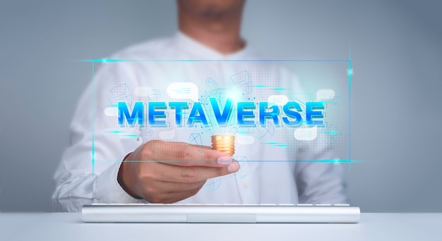 Virtuelle Wörter "METAVERSE" mit digitalen geometrischen Elementen und sozialen Netzwerk-Sprechblasensymbolen in der Cyberzone tauchen aus der kreativen Glühbirne in der Hand des Mannes mit Tastaturcomputer auf weißem Tisch auf.