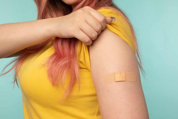 Virus Schutz. Aufgeregte geimpfte Frau, die Arm nach Injektionsstudiohintergrund mit leerem Raum zeigt. Coronavirus, Covid-19-Impfstoffkonzept.