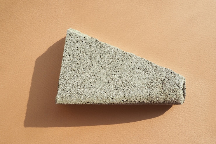 Foto viruta de hormigón sobre un fondo de papel beige en una luz dura con sombras. diseño plano, vista superior.
