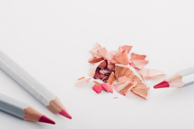 Virutas de lápiz cosmético rosa y lápices de colores sobre blanco