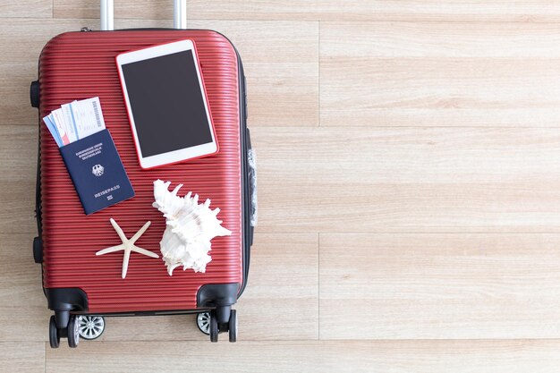 Visa de equipaje rojo y tableta van al aeropuerto en vacaciones divertidas las vacaciones de mar