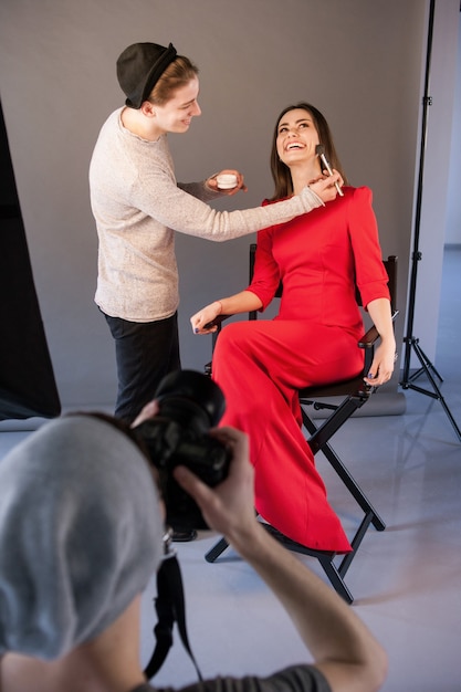 Visagist macht Make-up für glückliche Frau beim Fotoshooting