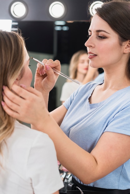 Foto visagiste beim augenbrauenmakeup für den kunden