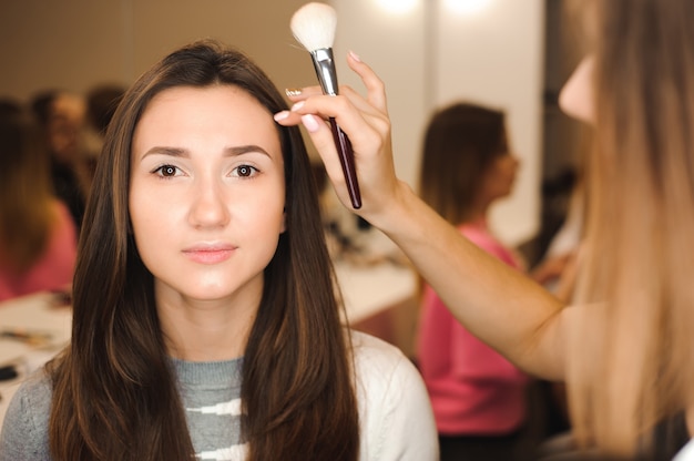 Visagistin, die professionelles Make-up der jungen Frau macht. Schönheit shcool.