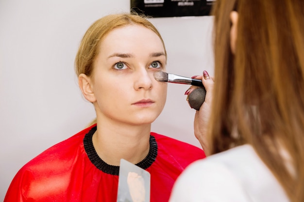 Visagistin macht Make-up für das Modell