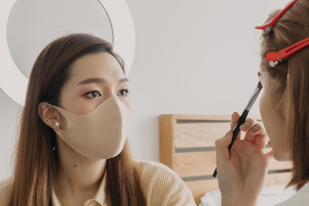 Visagistin trägt Make-up auf die Augen der Kunden auf