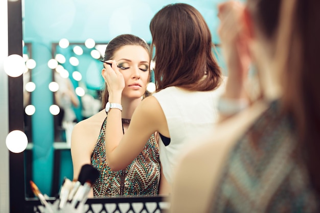 Visagistin und Model bei der Arbeit vor einem Spiegel