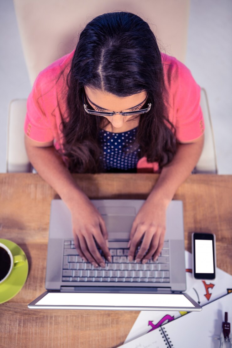 Foto visão aérea da empresária digitando no teclado do laptop no escritório criativo