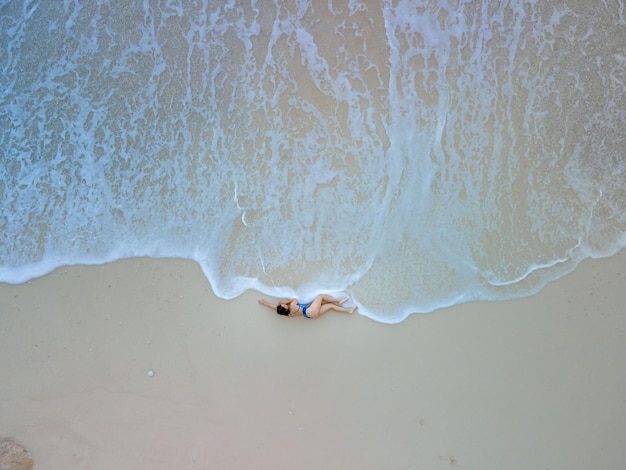 Visão aérea da mulher de maiô azul na praia do mar belas ondas