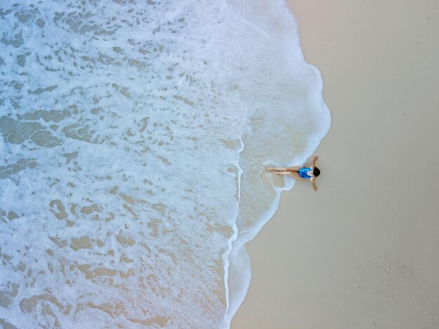 Visão aérea da mulher de maiô azul na praia do mar