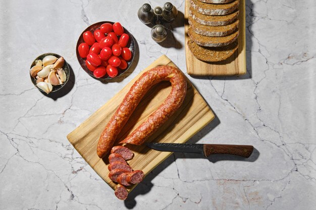 Visão aérea de anéis de salsicha de carne defumada na tábua de madeira na mesa da cozinha