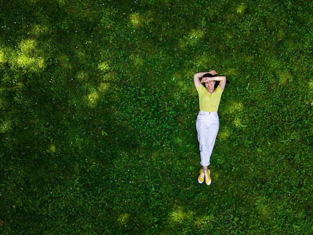 Visão aérea de uma mulher deitada na grama verde no verão