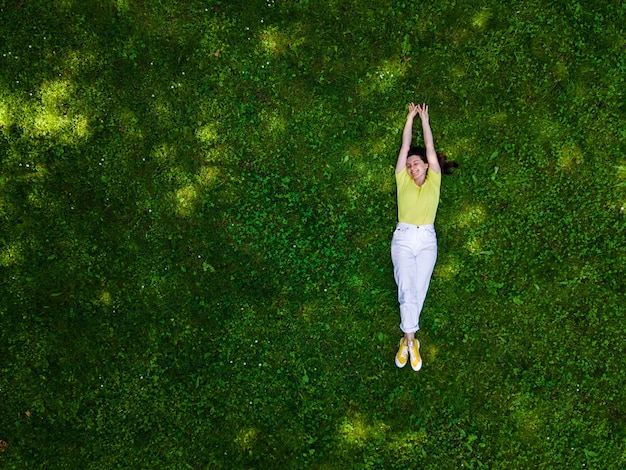 Visão aérea de uma mulher deitada na grama verde no verão