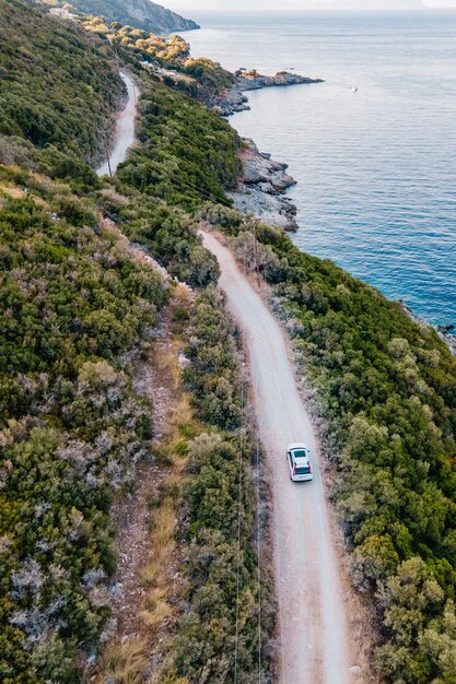 Visão aérea do carro em movimento pela estrada ao lado da costa do mar