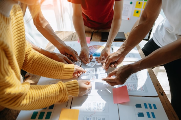 Visão aproximada da equipe de desenvolvedores de interface do usuário fazendo brainstorming em seu projeto com laptop, smartphone e tablet digital