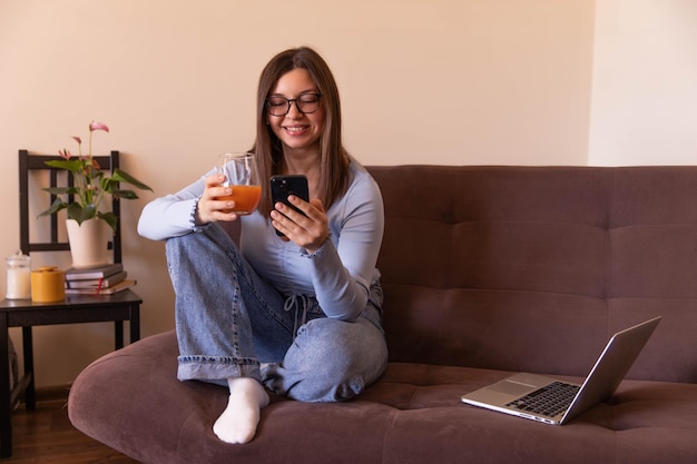 Visão completa da linda mulher olhando para o telefone e relaxando em casa