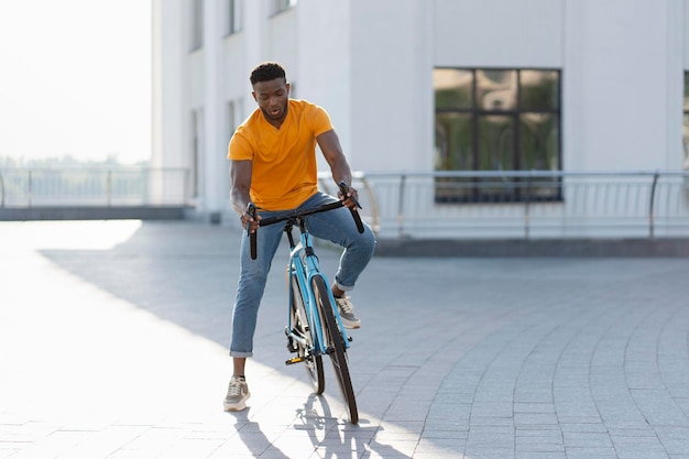 Visão completa de um homem afro-americano positivo preparando-se para andar de bicicleta na rua urbana conceito de estilo de vida ativo de passatempo esportivo